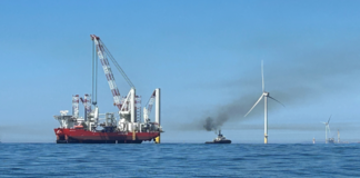 Eolico offshore: il Dipartimento dell’Interno USA riesamina l’approvazione di Revolution Wind due navi navigano vicino a una pala eolica off shore
