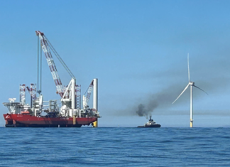 Eolico offshore: il Dipartimento dell’Interno USA riesamina l’approvazione di Revolution Wind due navi navigano vicino a una pala eolica off shore